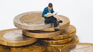 male figurine sitting on top of gold coins