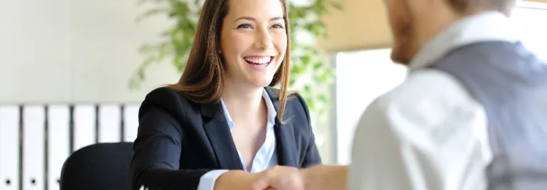Seated woman in corporate wear shaking hands with someone