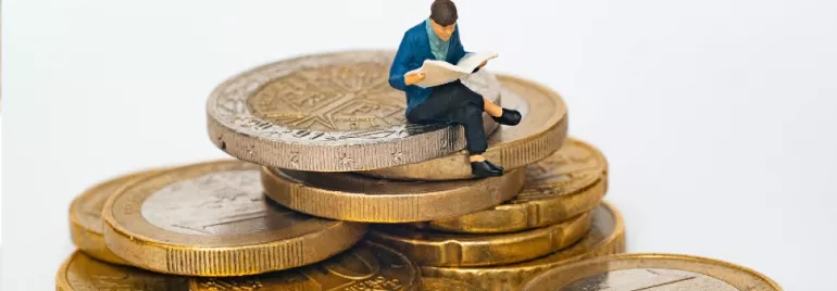 male figurine sitting on top of gold coins